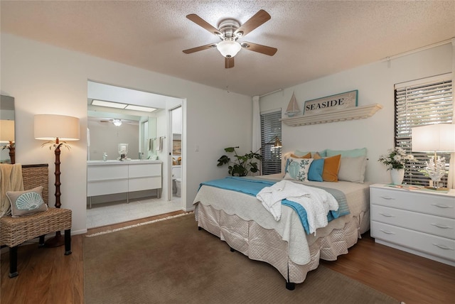 bedroom with ceiling fan, ensuite bathroom, dark hardwood / wood-style flooring, and a textured ceiling