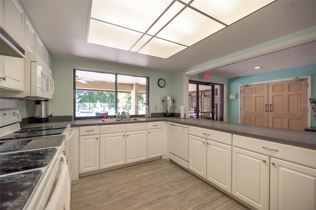 kitchen with sink, white cabinetry, white appliances, range hood, and light hardwood / wood-style floors