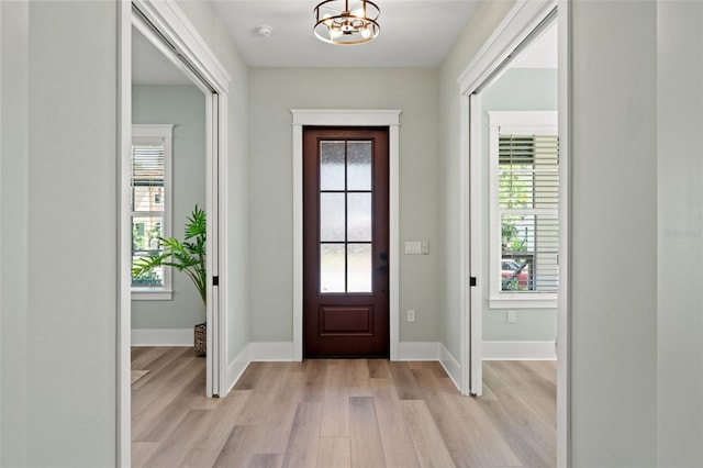 foyer featuring light wood-type flooring and a notable chandelier