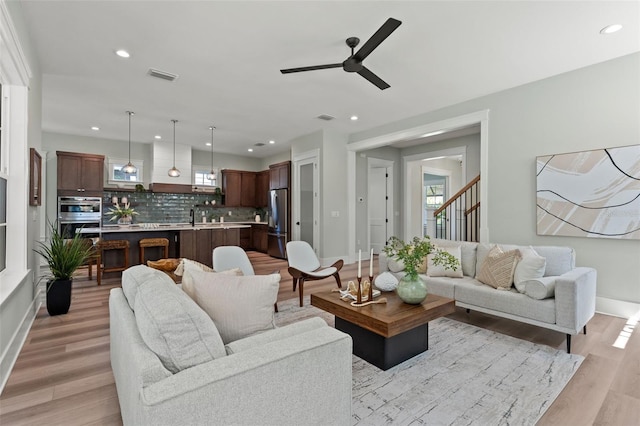 living room with sink, light hardwood / wood-style floors, a healthy amount of sunlight, and ceiling fan