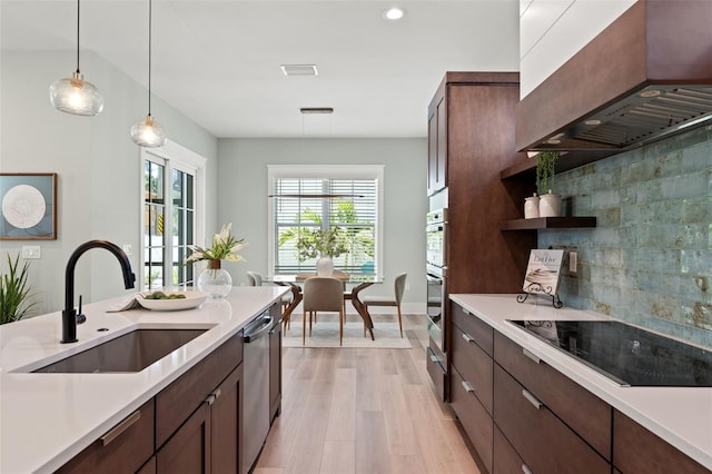 kitchen with pendant lighting, custom exhaust hood, black electric stovetop, sink, and stainless steel dishwasher