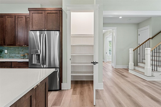 kitchen featuring stainless steel refrigerator with ice dispenser, decorative backsplash, and light hardwood / wood-style floors