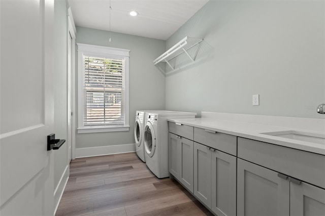 laundry area featuring sink, light wood-type flooring, cabinets, and washer and clothes dryer