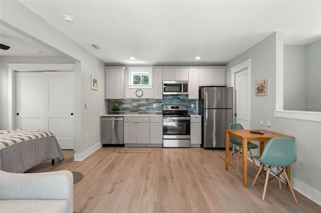 kitchen featuring light hardwood / wood-style floors, appliances with stainless steel finishes, tasteful backsplash, white cabinetry, and sink