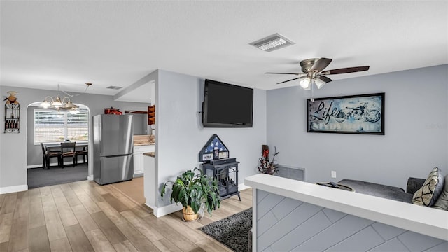 interior space with ceiling fan with notable chandelier and light hardwood / wood-style floors