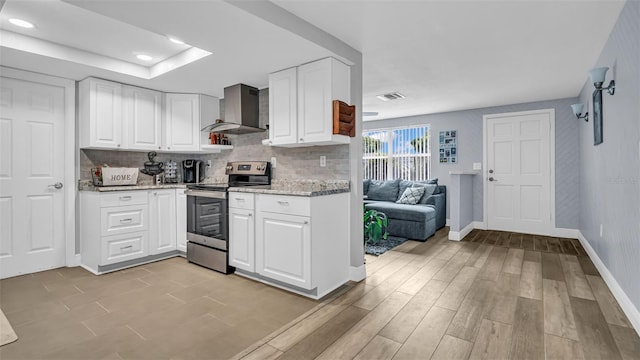 kitchen featuring white cabinets, stainless steel electric range, light stone countertops, and wall chimney exhaust hood