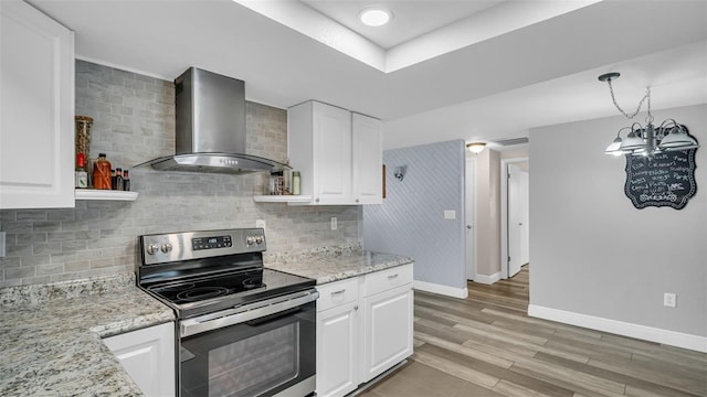 kitchen featuring white cabinetry, light stone counters, decorative light fixtures, stainless steel range with electric cooktop, and wall chimney exhaust hood