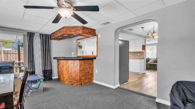 interior space with ceiling fan, bar, and a drop ceiling