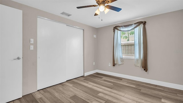 unfurnished bedroom featuring ceiling fan, a closet, and light hardwood / wood-style flooring