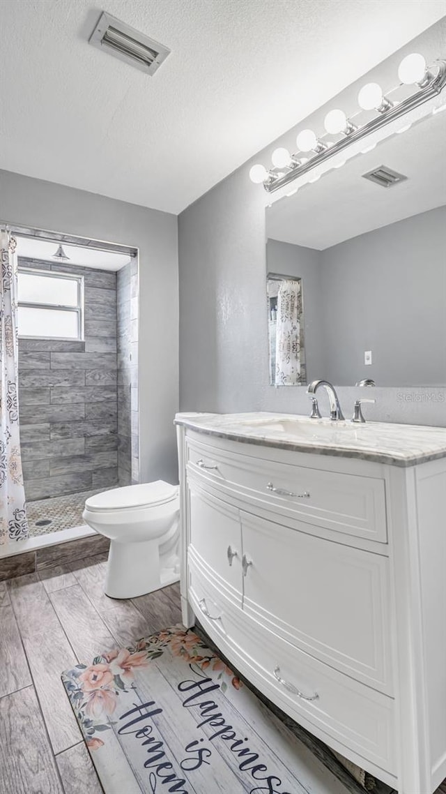 bathroom featuring vanity, a textured ceiling, toilet, and a shower with shower curtain