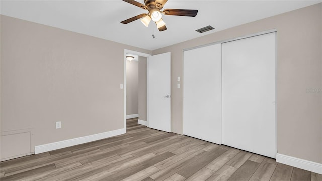 unfurnished bedroom with light wood-type flooring, ceiling fan, and a closet