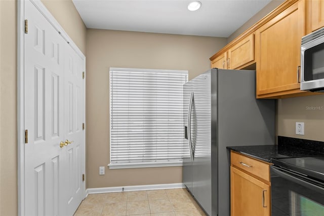 kitchen featuring stainless steel appliances, light tile patterned floors, and dark stone counters