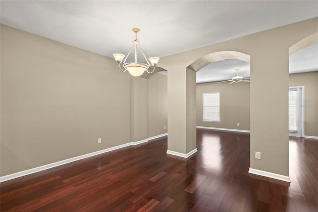 interior space with ceiling fan with notable chandelier and dark hardwood / wood-style floors