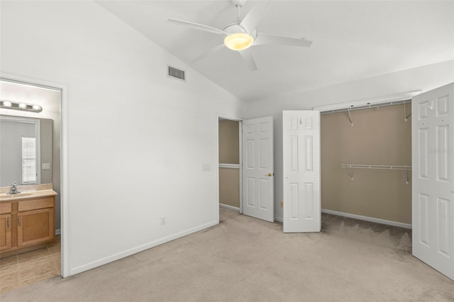 unfurnished bedroom with lofted ceiling, ensuite bath, light carpet, a closet, and ceiling fan