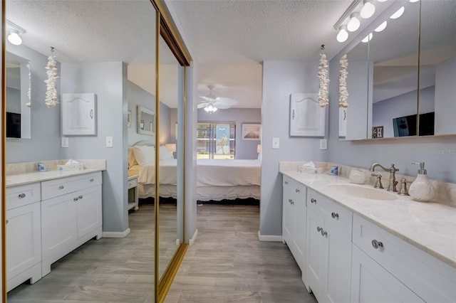 bathroom with hardwood / wood-style flooring, ceiling fan, and a textured ceiling