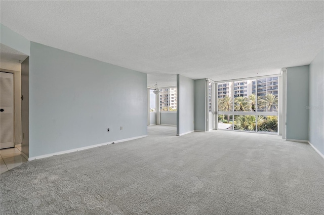 carpeted spare room featuring floor to ceiling windows and a textured ceiling