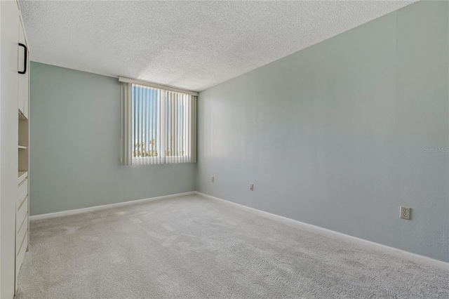 unfurnished room with light colored carpet and a textured ceiling