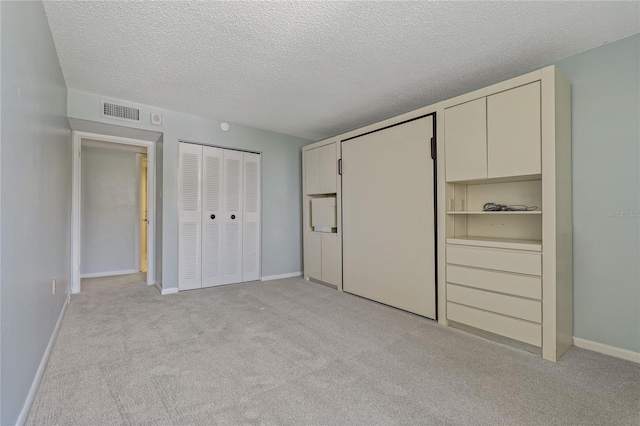 unfurnished bedroom featuring light carpet and a textured ceiling