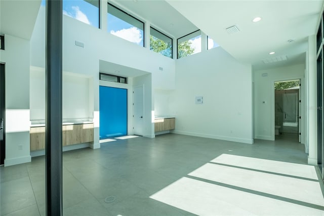 unfurnished living room with a towering ceiling and tile patterned floors