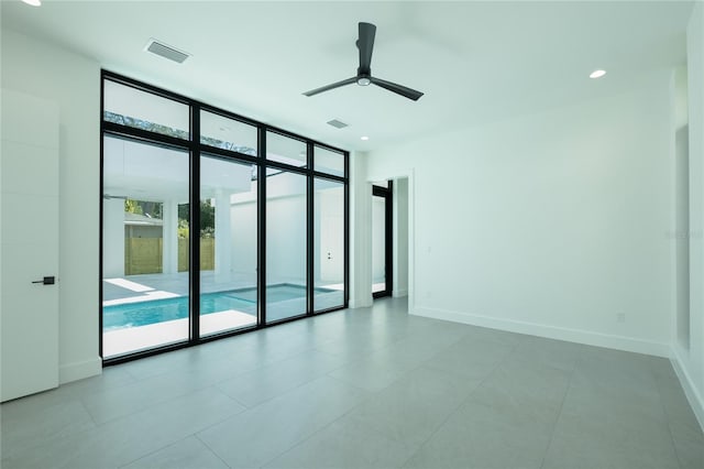 unfurnished room with ceiling fan, expansive windows, and tile patterned flooring