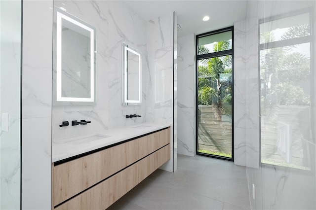 bathroom with tile walls, tile patterned flooring, vanity, and a healthy amount of sunlight