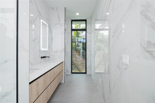 bathroom with tile walls, tile patterned flooring, vanity, and floor to ceiling windows