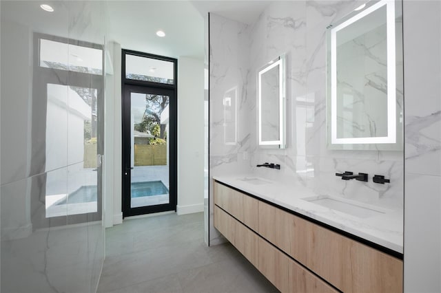 bathroom featuring tile walls, tasteful backsplash, double sink vanity, and tile patterned floors