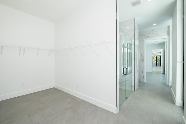 walk in closet with light tile patterned floors