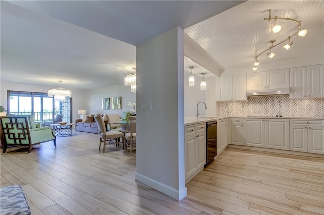 kitchen featuring sink, tasteful backsplash, a notable chandelier, light hardwood / wood-style floors, and white cabinets