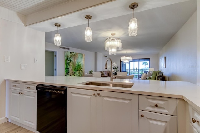 kitchen featuring white cabinetry, sink, hanging light fixtures, and black dishwasher