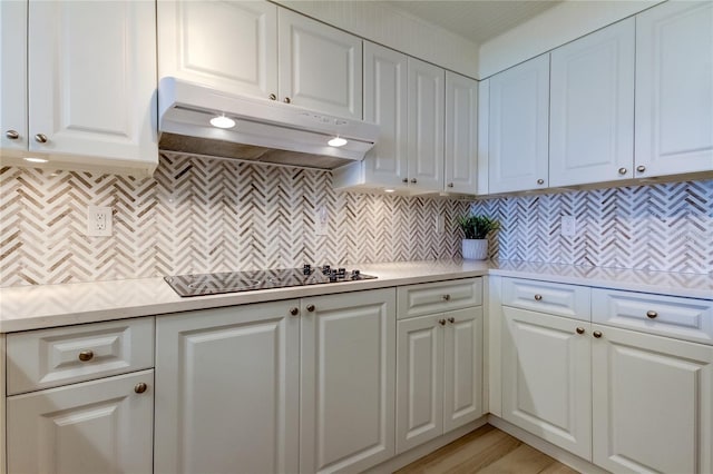 kitchen featuring light wood-type flooring, black electric stovetop, white cabinets, and backsplash