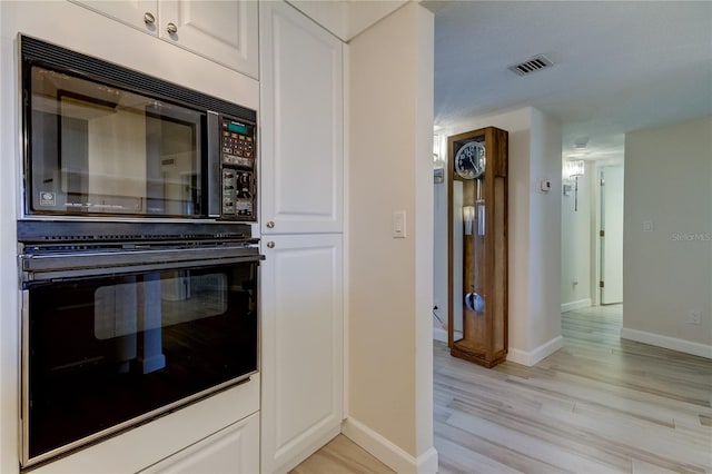 kitchen with white cabinets, light wood-type flooring, and black appliances