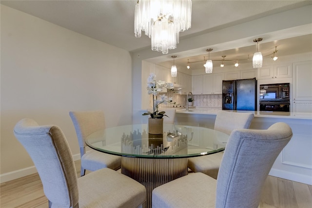 dining room featuring sink, a chandelier, and light wood-type flooring