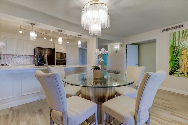 dining room with an inviting chandelier and light hardwood / wood-style flooring