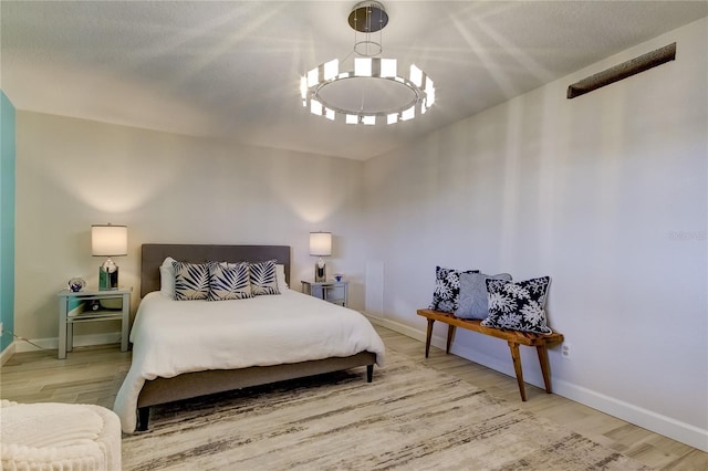 bedroom featuring an inviting chandelier and wood-type flooring