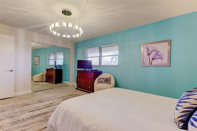 bedroom with hardwood / wood-style floors, a chandelier, and a closet