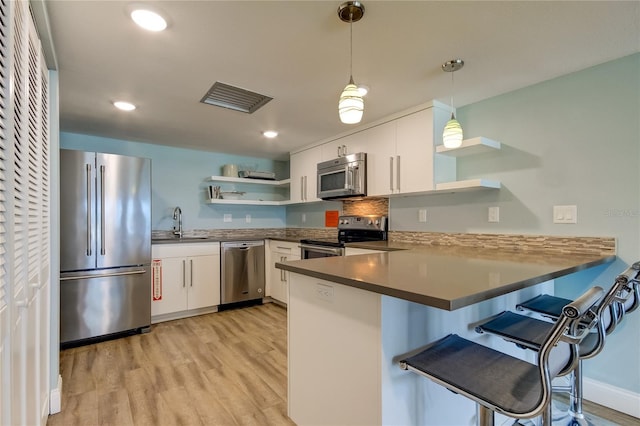 kitchen featuring white cabinetry, stainless steel appliances, decorative light fixtures, and kitchen peninsula