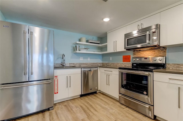 kitchen with sink, white cabinetry, tasteful backsplash, appliances with stainless steel finishes, and light hardwood / wood-style floors