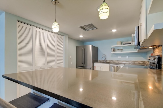 kitchen featuring a breakfast bar, white cabinetry, decorative light fixtures, appliances with stainless steel finishes, and kitchen peninsula