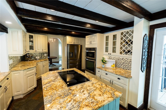 kitchen with white cabinetry, appliances with stainless steel finishes, a center island, and light stone countertops