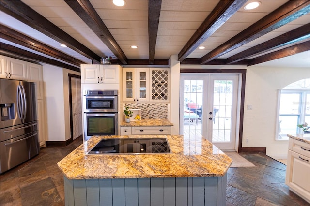 kitchen featuring light stone counters, a kitchen island, white cabinets, and appliances with stainless steel finishes