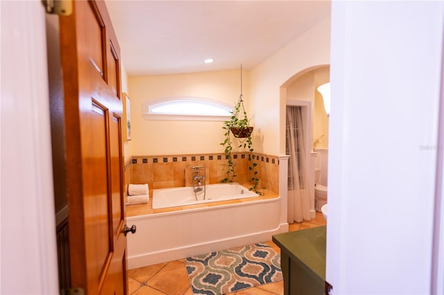 bathroom featuring tile patterned flooring, a bathing tub, vanity, and toilet