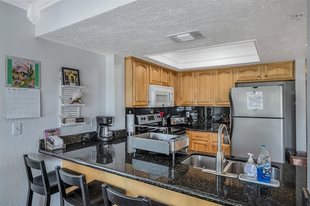 kitchen with visible vents, dark stone counters, appliances with stainless steel finishes, a peninsula, and a textured ceiling