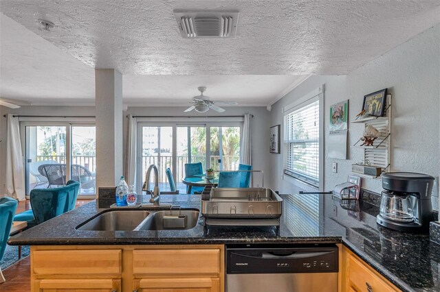 kitchen with visible vents, a textured wall, a ceiling fan, a sink, and dishwasher