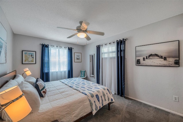 carpeted bedroom featuring baseboards, multiple windows, a ceiling fan, and a textured ceiling