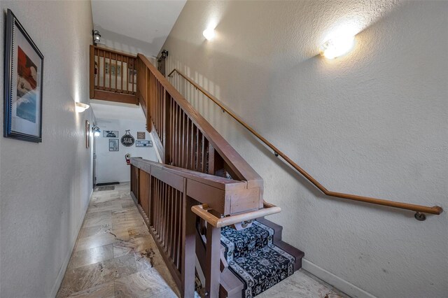 stairs with stone finish floor, baseboards, and a textured wall