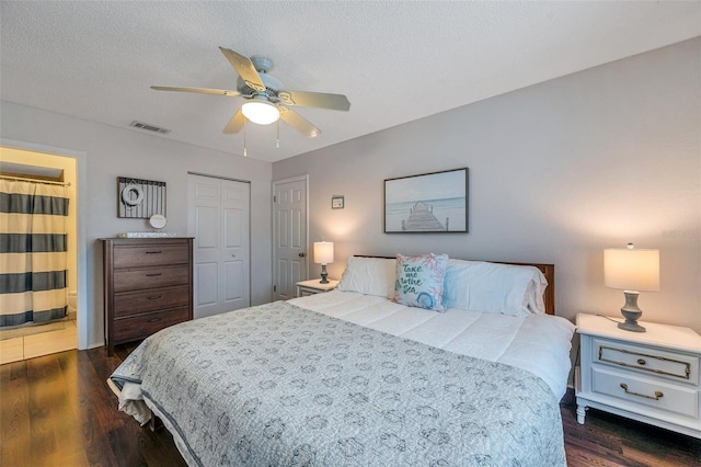 bedroom featuring a closet, dark wood-style flooring, visible vents, and a textured ceiling