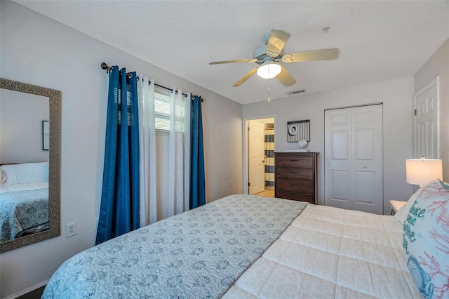 bedroom with a textured ceiling, ceiling fan, a closet, and visible vents