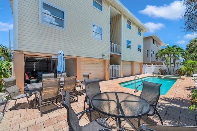 exterior space featuring a pool with connected hot tub, outdoor dining area, a patio area, and fence