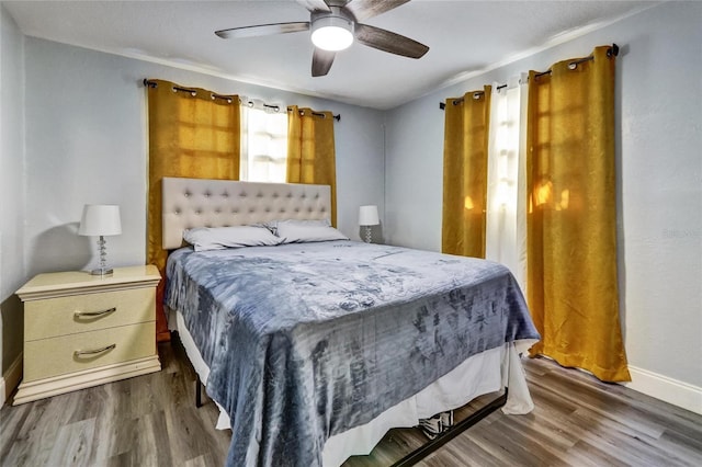 bedroom with dark wood-style floors, ceiling fan, and baseboards